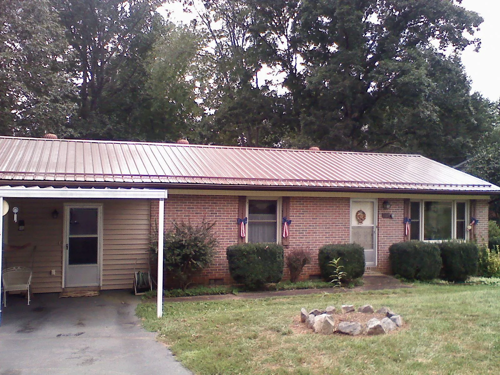 Bronze metal roof and carport on a brick ranch home — Roof Repair work by our crew in Lumberton